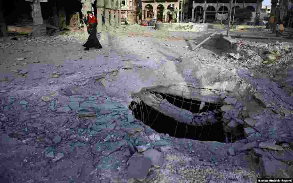 A Syrian woman walks past damaged buildings in Douma, in the eastern Damascus suburb of Ghouta. (Reuters/Bassam Khabieh)