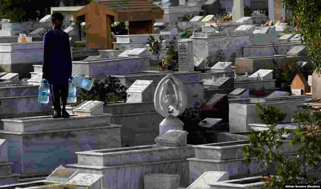 A boy with water for sale stands on a grave while waiting for customers in a cemetery in Karachi, Pakistan. (Reuters/Akhtar Soomro)