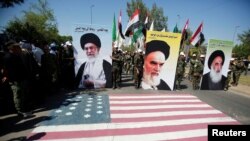 Iraqi Shi'ite Muslims from Hashid Shaabi hold portraits of Iran's late leader Ayatollah Ruhollah Khomeini (C), Supreme Leader Ayatollah Ali Khamenei (L) and Iraq's Grand Ayatollah Ali al-Sistani during a parade, as they get ready to trample upon the U.S. flag. June 2016