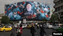 Люди проходят мимо щита с изображением покойного президента Ирана Ибрагима Раиси на улице в Тегеране, Иран, 21 мая 2024 года