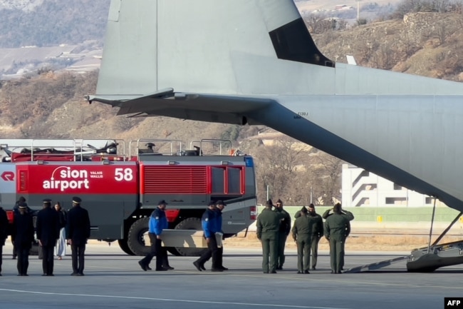Policë zviceranë, duke transportuar një arkivol në bordin e një avioni C-130 Hercules të Forcave Ajrore Italiane, gjatë riatdhesimit të trupave të pesë prej gjashtë shtetasve italianë që humbën jetën në tragjedinë e zjarrit të Vitit të Ri.