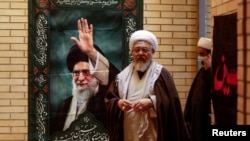 Верски лидери поминуваат покрај ѕид со постер од врховниот лидер на Иран, ајатолахот Али Хамнеи