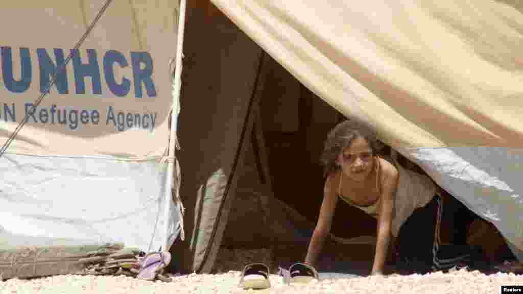 A Syrian refugee girl looks out from a tent amid dust at the Al-Zaatri refugee camp in the city of Mafraq, Jordan. (Reuters/Majed Jaber)