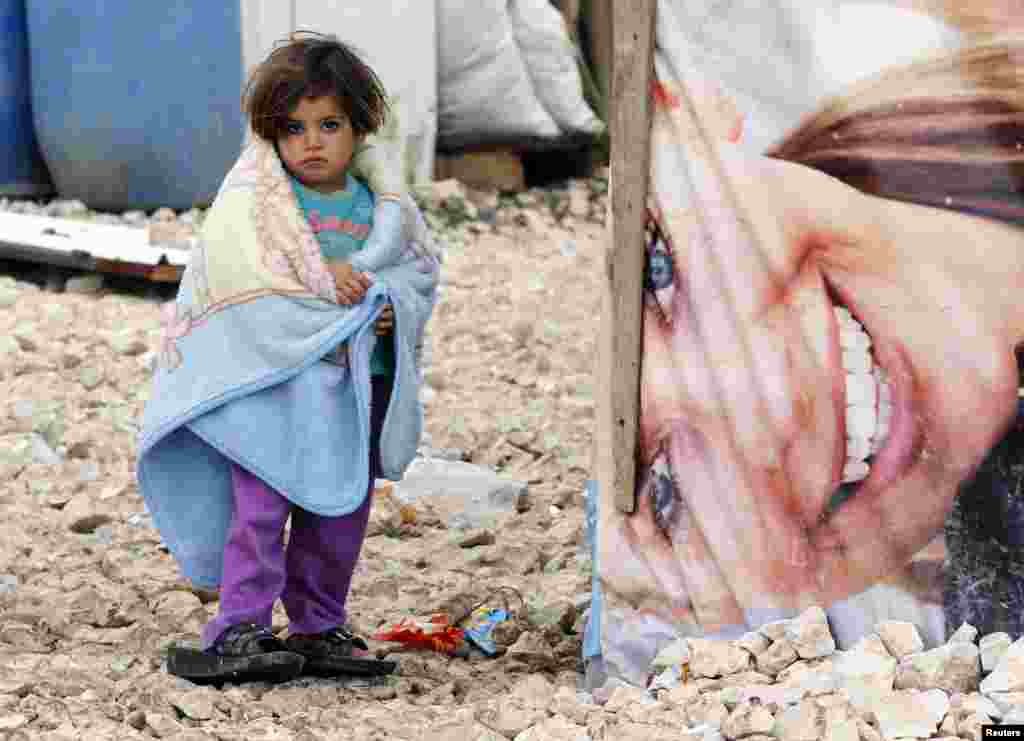 A Syrian refugee girl covers herself with a blanket as she stands outside tents in a makeshift settlement in Bar Elias in Lebanon&#39;s Bekaa Valley. (Reuters/​Mohamed Azakir)