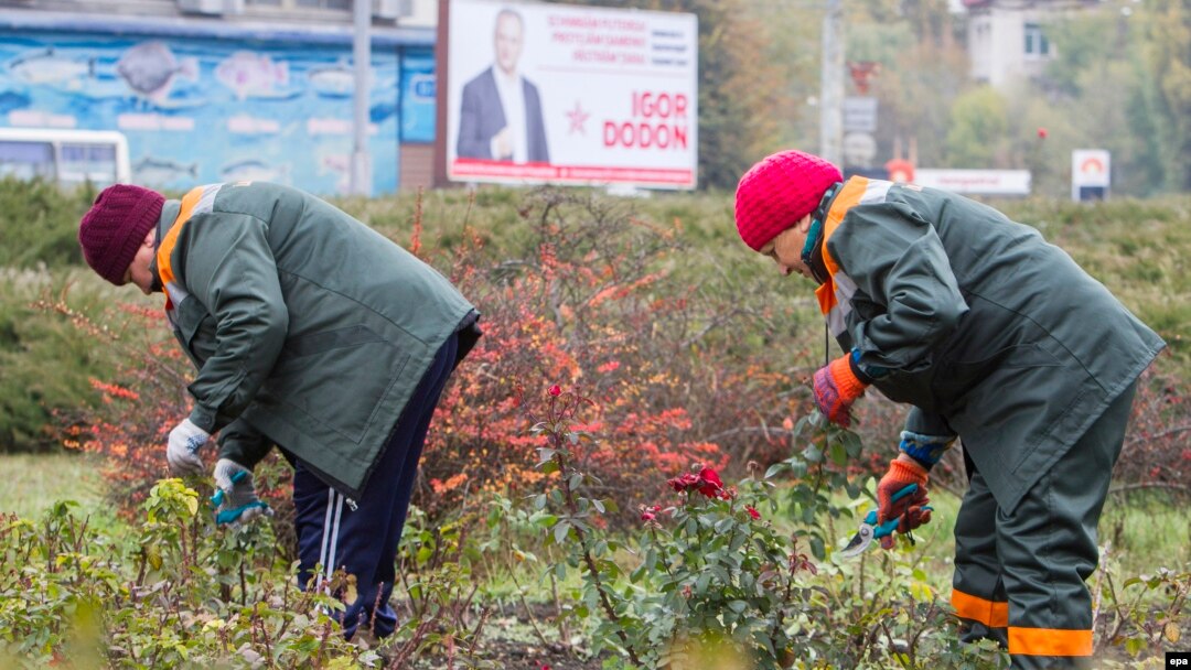 Two Moldovan women work against the backdrop of an electoral campaign poster for presidential front-runner Igor Dodon in Chisinau on October 27. 