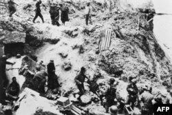 Soldați americani din Batalionul 2 Ranger înconjoară prizonieri germani, la 6 iunie 1944, pe Pointe du Hoc, situat pe o stâncă ce domină plaja Omaha Beach, după ce forțele aliate au luat cu asalt plajele din Normandia în timpul Zilei Z.