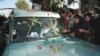 IRAN - An Iranian mourner layes red roses on the ambulance that carries the coffin of Iranian poet Ahmad Shamlou during his funeral in Tehran 27 July 2000