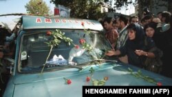 IRAN - An Iranian mourner layes red roses on the ambulance that carries the coffin of Iranian poet Ahmad Shamlou during his funeral in Tehran 27 July 2000