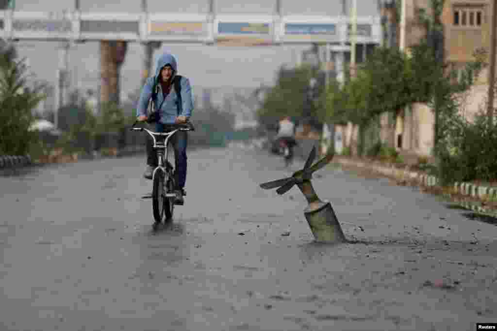 A resident rides his bicycle past what activists said was an exploded cluster bomb.