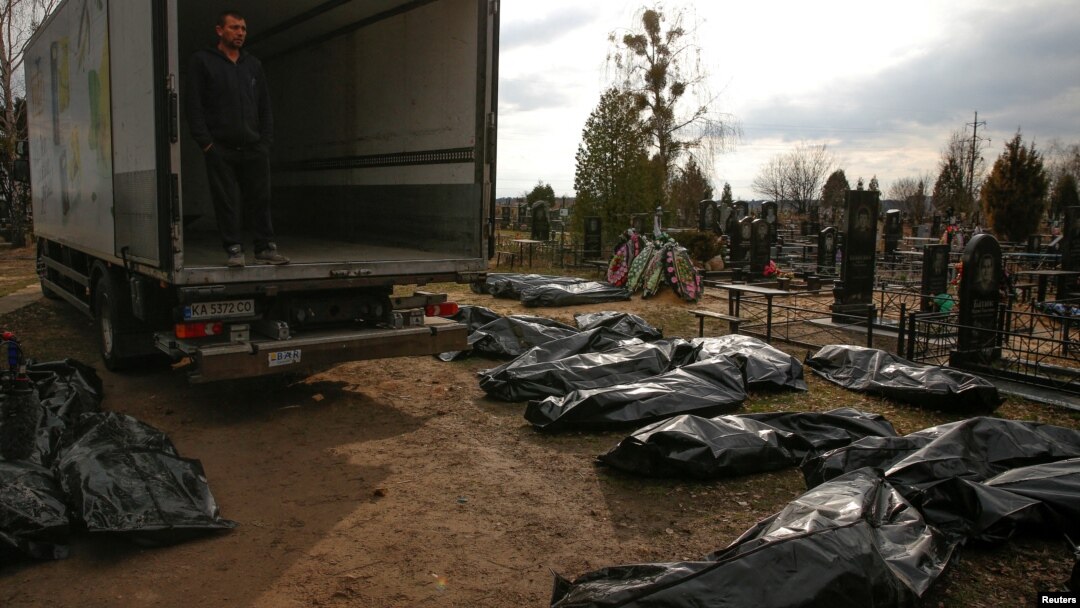A funeral service employee looks at the bodies of civilians collected from the streets of Bucha at a local cemetery.