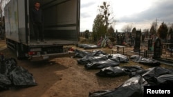 A funeral service employee looks at the bodies of civilians collected from the streets of Bucha at a local cemetery.