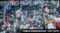 People hold up lights, Slovak and EU flags as they take part in an antigovernment protest at Bratislava's Freedom Square, February 7, 2025. 