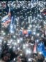 People hold up lights, Slovak and EU flags as they take part in an antigovernment protest at Bratislava's Freedom Square, February 7, 2025. 