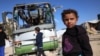 Mai mulți copii se uită la carcasa unui autobuz distrus de un atac israelian în zona Mawasi, la vest de orașul Khan Yunis, în sudul Fâșiei Gaza, pe 23 decembrie 2024.