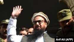 Hafiz Saeed waves to supporters as he leaves a court in Lahore on November 21