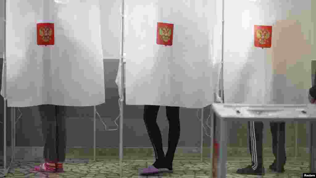 Voters fill out ballot papers in booths at a polling station in a student hostel in the southern city of Stavropol.