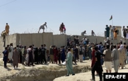 Люди намагаються через огороджувальну стіну потрапити на територію аеропорту у Кабулі, захопленому талібами. Афганістан. 16 серпня 2021 року