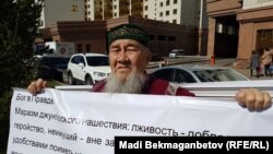 Житель Астаны Ибрагим Козыбаев развернул баннер в попытке провести одиночную акцию у здания Союза журналистов. Астана, 21 мая 2018 года.