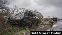 Військовослужбовець 24-ї ОМБр ЗСУ йде повз пошкоджену військову машину з антидроновим захистом, Дружківка, Донецька область, 24 квітня 2026 року