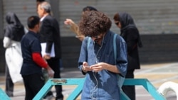 A man uses his mobile phone while standing on Valiasr Square in Tehran on April 19.