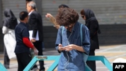 A man uses his mobile phone while standing on Valiasr Square in Tehran on April 19.