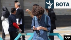 Një burrë përdor telefonin e tij celular në sheshin "Valiasr" në Teheran, më 19 prill.