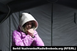 O tânără se încălzește într-o stație mobilă unde locuitorii din Kiev se pot încălzi, pot bea ceai, își pot încărca dispozitivele și pot primi asistență în timpul întreruperilor de curent și încălzire. Districtul Dniprovskyi, Kiev, 20 ianuarie 2026.