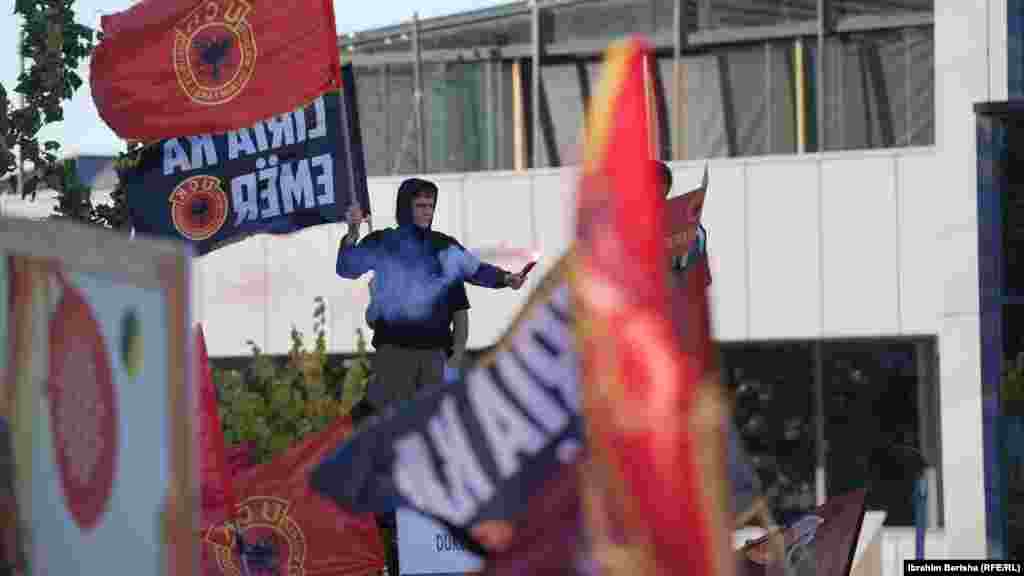 Një protesues i ri mban në dorën e djathtë flamurin e UÇK-së, ndërsa në të majtën një flakadanë.Për shumë njerëz në Kosovë, aktgjykimi e cilëson UÇK-në si "organizatë të përbashkët kriminale", megjithëse vetë kryetari i trupit gjykues nguli këmbë disa herë në aktgjykim se lufta e UÇK-së për liri nuk u gjykua.