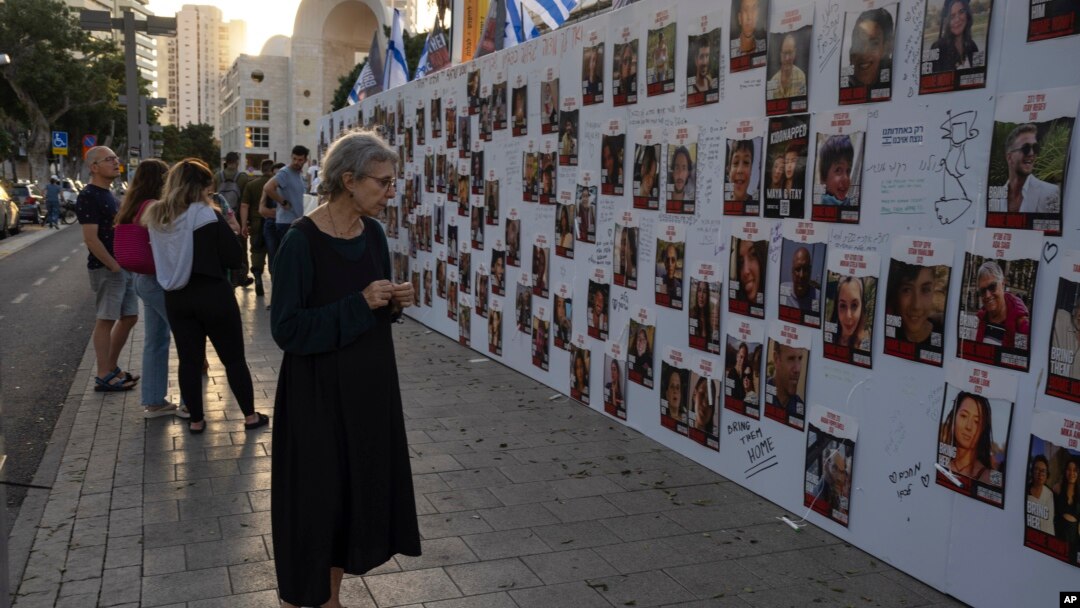 O femeie privește fotografiile israelienilor dispăruți și ținuți prizonieri în Gaza, expuse pe un perete din Tel Aviv, pe 20 octombrie 2023.