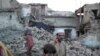 Residents walk past the rubble of a house after it was damaged by an earthquake in Swat on October 26.