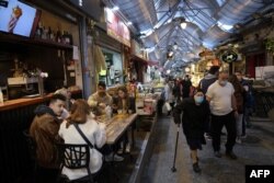 Люди їдять у ресторані на головному ринку Єрусалиму після того, як влада 11 березня 2021 року знову відкрила ресторани, бари та кафе для власників «зеленої перепустки» (доказу отримання вакцини covid-19).