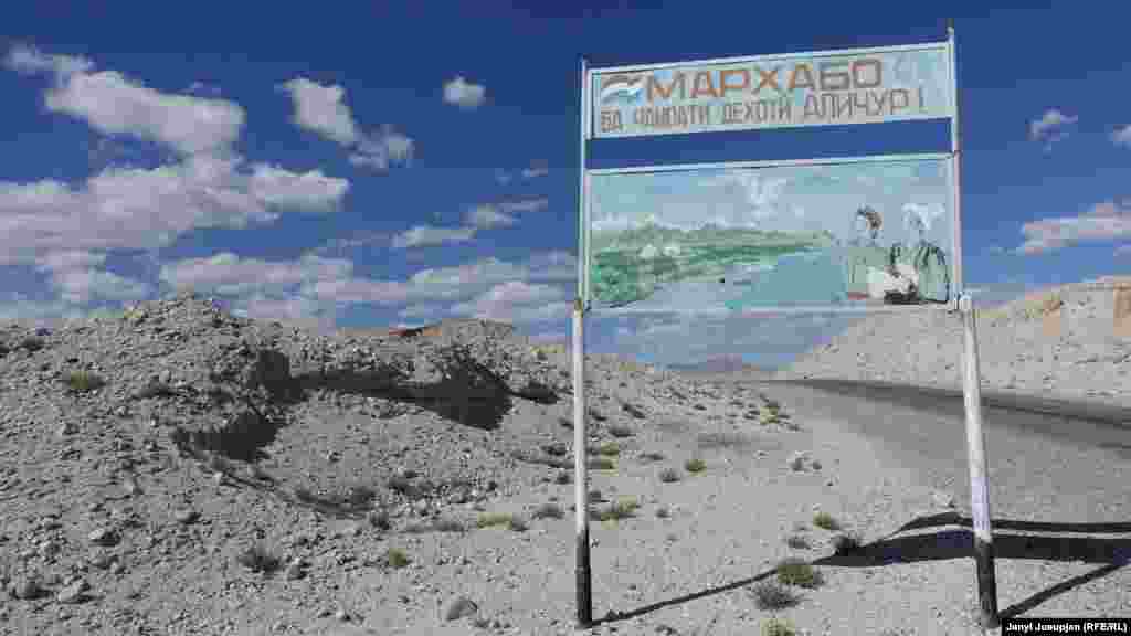 A Soviet-style billboard welcomes travellers to Alichor with a depiction of two men, one with a Kyrgyz white hat and one with the red hat of the Pamiri ethnic group.