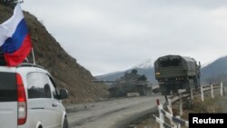 NAGORNO-KARABAKH -- Military vehicles of the Russian peacekeeping forces drive along a road past a burnt tank near Shusha (Shushi), November 13, 2020