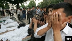 People pray on May 14, 2005, by the bodies of victims of the government crackdown in Andijon.