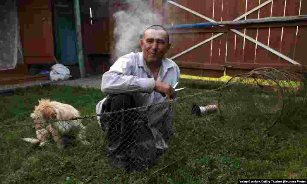 A man mends fishing nets in his backyard.