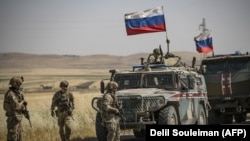Солдаты США стоят перед российской военной техникой в северо-восточном сирийском городе Аль-Маликия (Дерик) на границе с Турцией, 3 июня 2020 года
