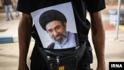یک زائر محرم در مرز چذابه عکسی از مجتبی خامنه‌ای را با خود حمل می‌کند