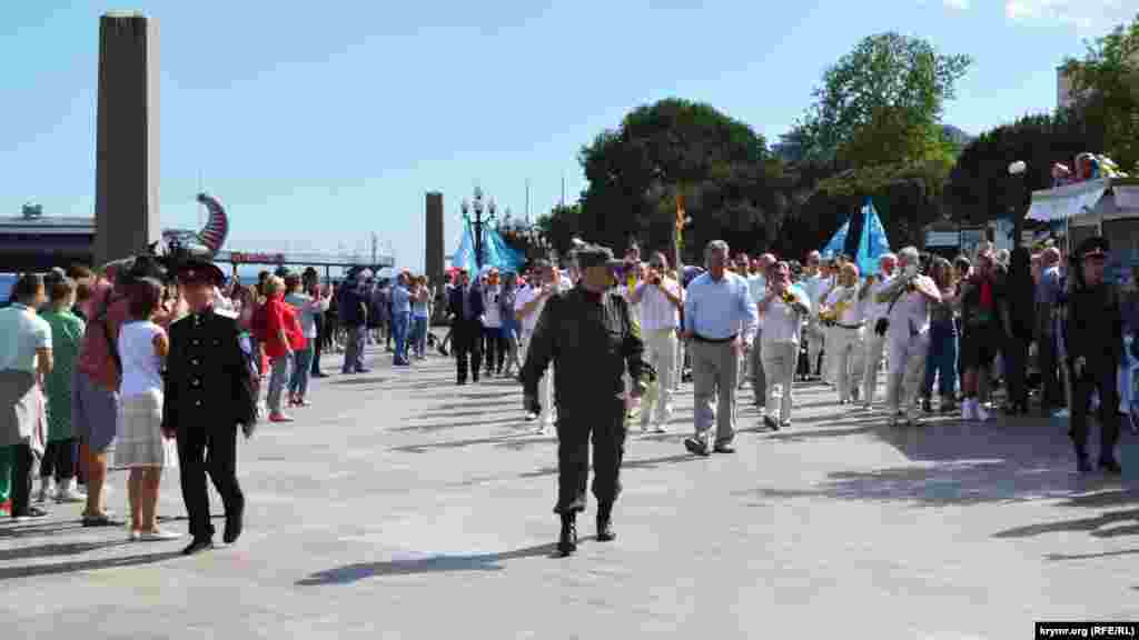 Egizlerniñ yanında asker formalı adamlar. Kolonnanıñ yanında rusiye polisi hadimleri, &quot;Qırım samooboronası&quot; hadimleri ve &quot;Qırım qazaqlığı&quot;nıñ vekilleri kete