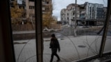 A photographer walks past buildings damaged by a Russian military strike in the town of Pokrovsk