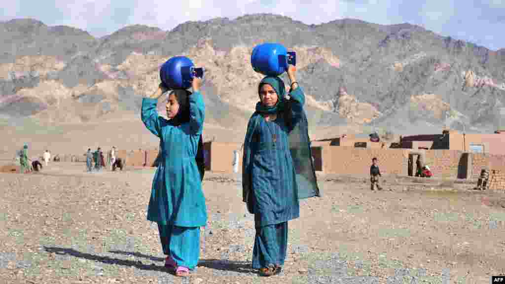 Internally displaced women in Afghanistan carry gas cylinders on their heads on the outskirts of Herat. (AFP/Aref Karimi)