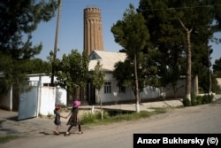 Two local girls walk near a 900-year-old minaret in the southern town of Minor, near the border with Afghanistan.