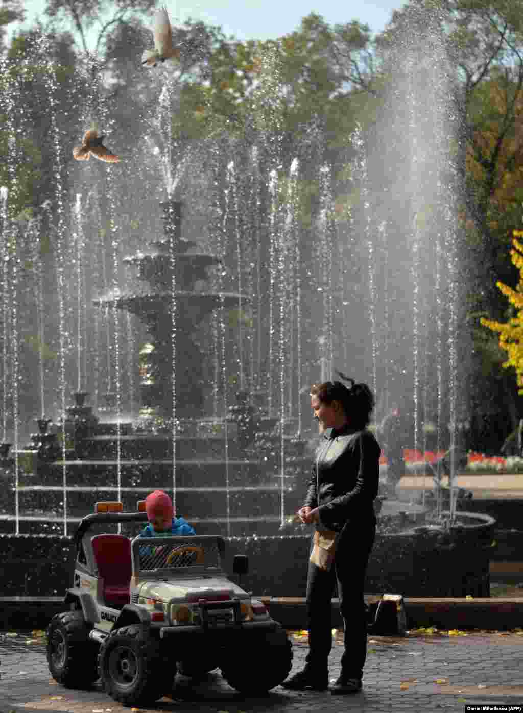 A child plays near a fountain in a downtown park.