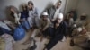 Students wear chains around their ankles while sitting with their belongings at a police station after being rescued during a late-night raid on December 12-13 at the Zakariya madrasah on the outskirts of Karachi.