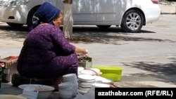 Жительница Ашхабада моет посуду во дворе многоэтажного дома. (Иллюстративное фото)