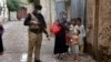 A police officer stand guard while a health-care worker administers a polio vaccine to a child as part of a national inoculation campaign. (file photo)