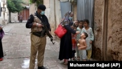 A police officer stand guard while a health-care worker administers a polio vaccine to a child as part of a national inoculation campaign. (file photo)