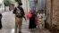 A police officer stand guard while a health-care worker administers a polio vaccine to a child as part of a national inoculation campaign. (file photo)