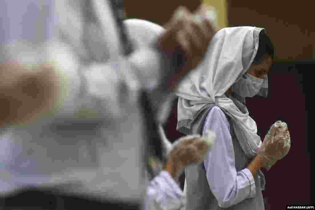 Egy diák arcmaszkban és kesztyűben egy iskolai gyülekezőn Pakisztánban szeptember 15-én.