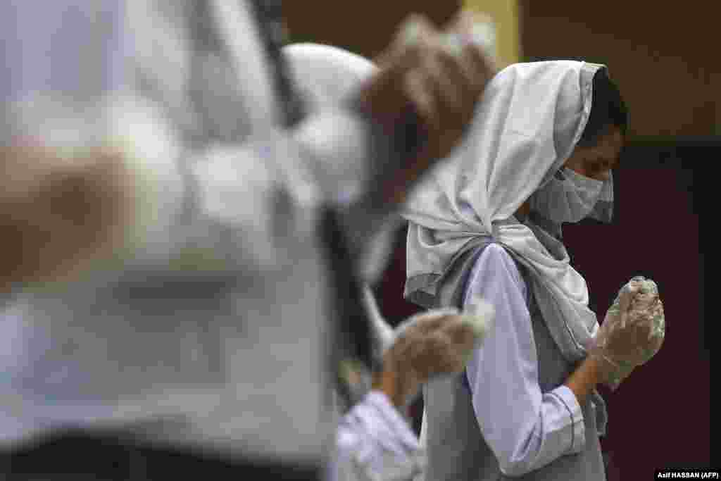 A student wearing a face mask and gloves takes part in an assembly at a school in Karachi, Pakistan, on September 15 after educational institutions reopened.