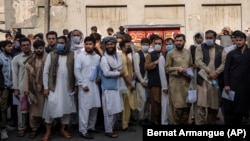 Afghans line up outside the Iranian Embassy in Kabul to request travel visas on September 29.